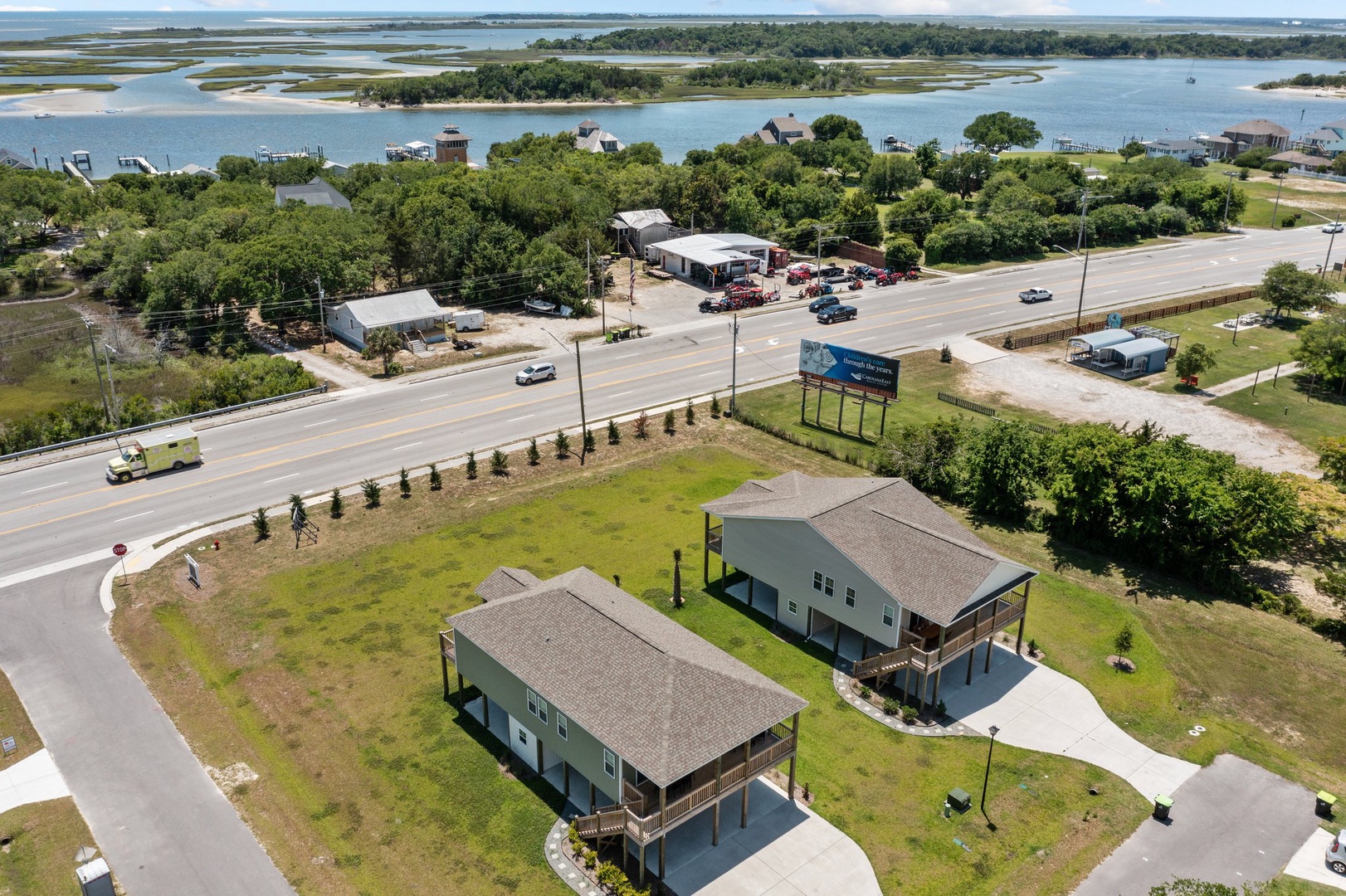 Aerial view of waterfront vacation rentals situated along scenic coastal marshlands with convenient highway access and local amenities nearby.