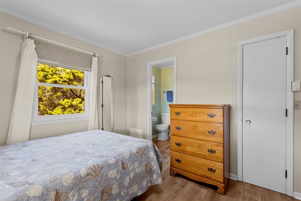 Cozy bedroom with wooden dresser, soft linens, and autumn views through your window.