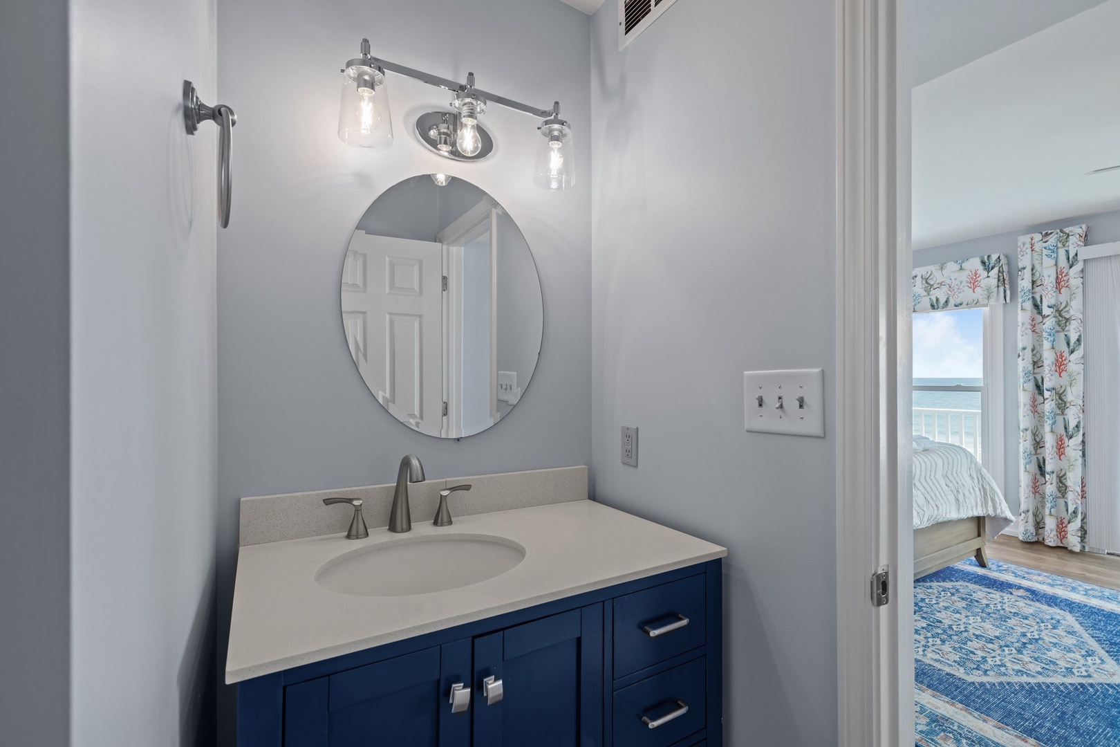 Your elegant bathroom vanity features beautiful navy cabinetry, stylish lighting, and modern finishes for a refined coastal experience.