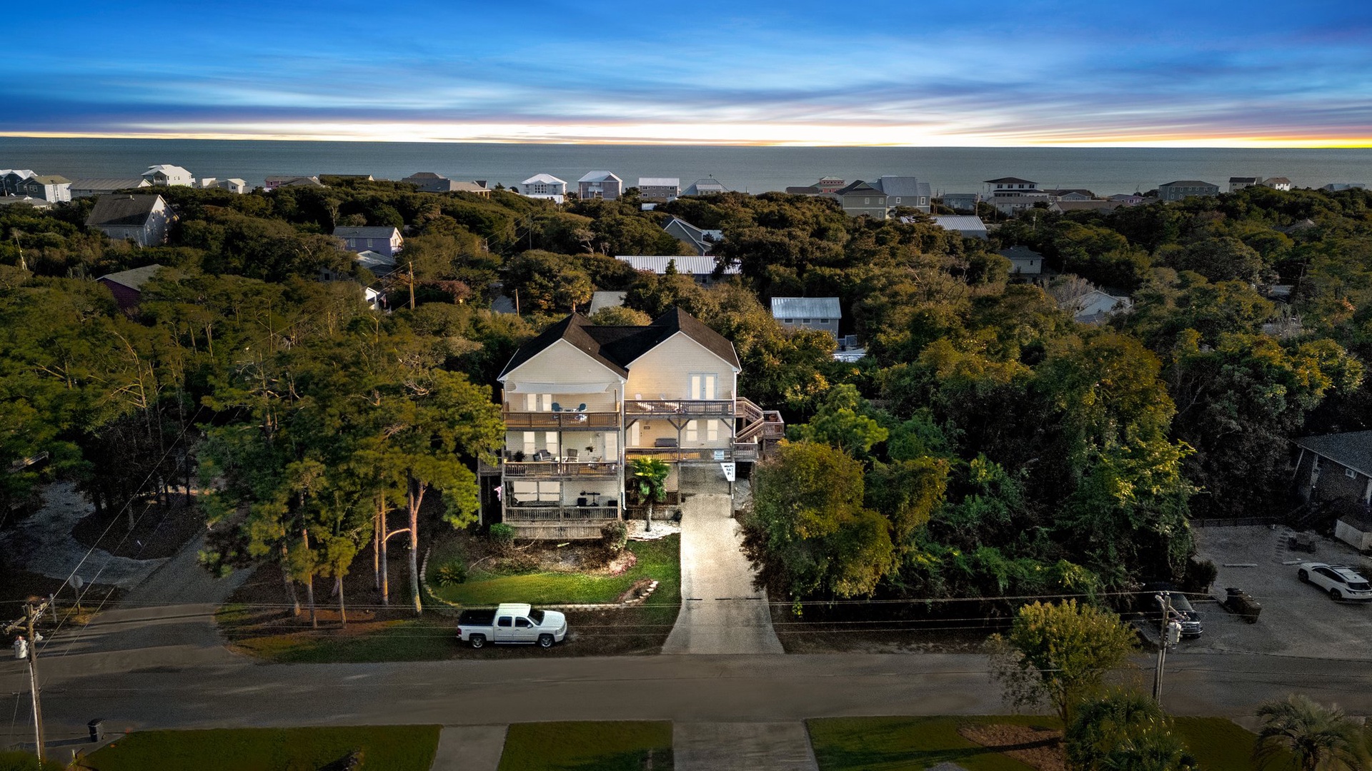 Aerial view of beachside property nestled among coastal trees with ocean views in the distance.
