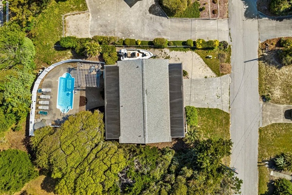 Aerial view showing the property nestled among lush greenery with a sparkling pool and well-maintained grounds.