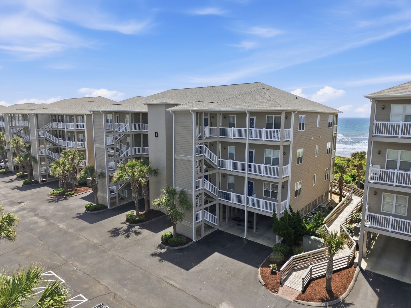 Beachfront property with spacious balconies and direct ocean access, surrounded by palm trees and steps from the shore.