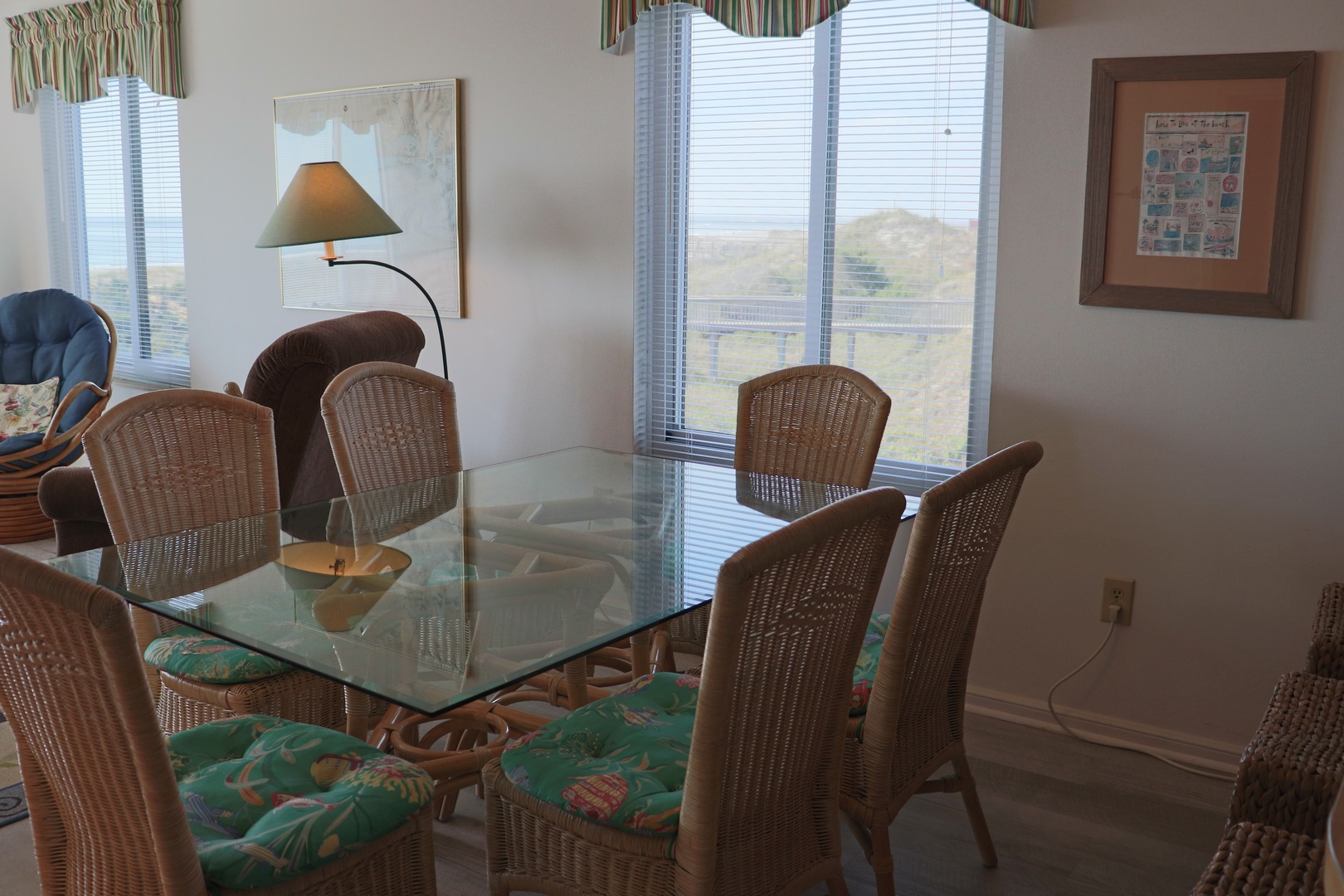 Gather around your elegant glass dining table with wicker chairs, where natural light streams through large windows creating the perfect atmosphere for memorable meals.