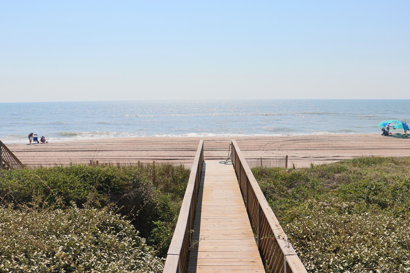 Sandy beach with wooden walkway providing direct access to the shoreline and ocean views.