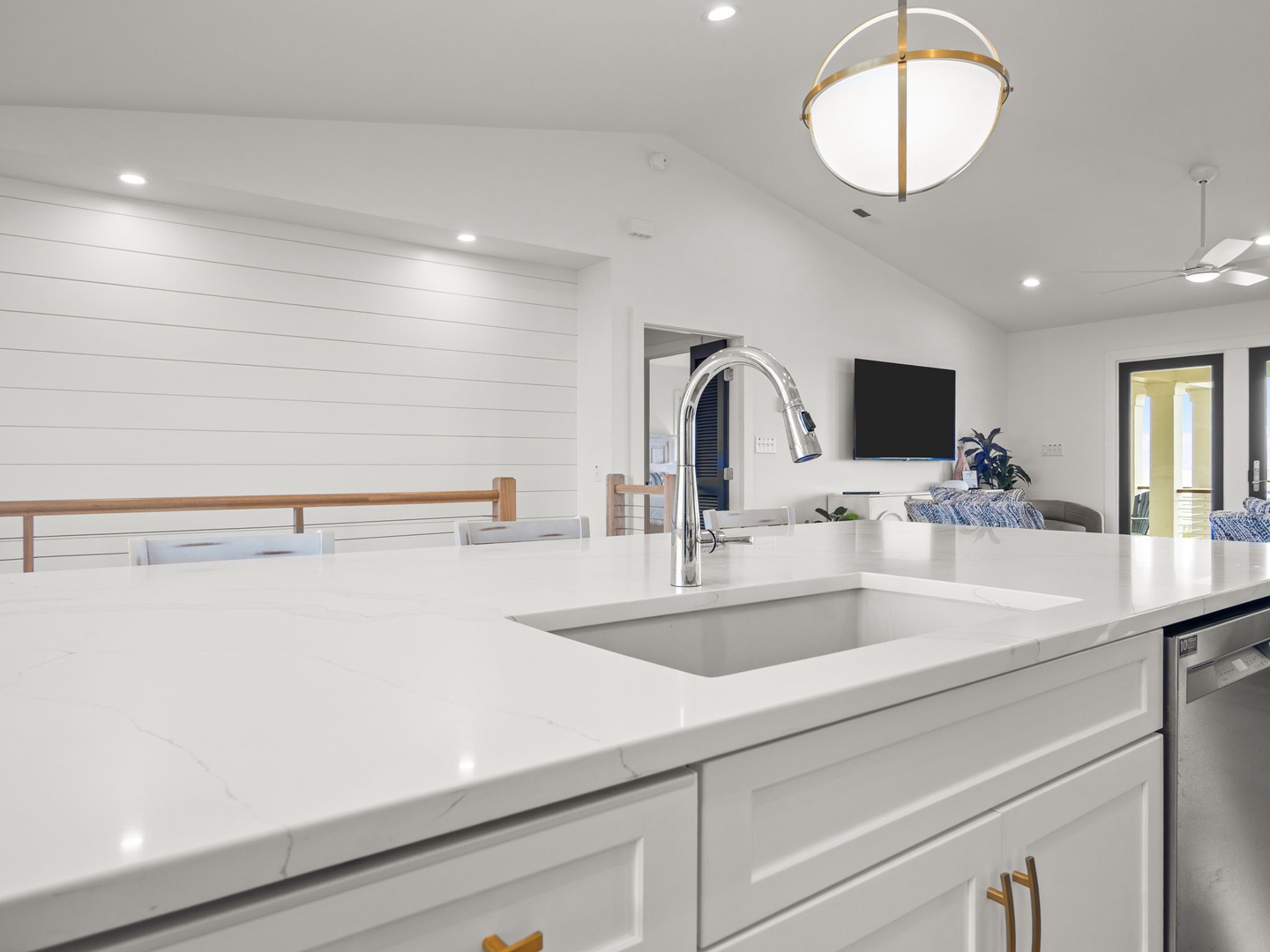 Your modern kitchen features pristine white quartz countertops and stainless steel appliances, perfect for preparing meals while chatting with loved ones in the open dining area.