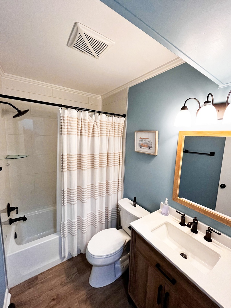 Step into your stylish bathroom with soothing blue walls, modern vanity, and relaxing tub-shower combo for unwinding after adventures.