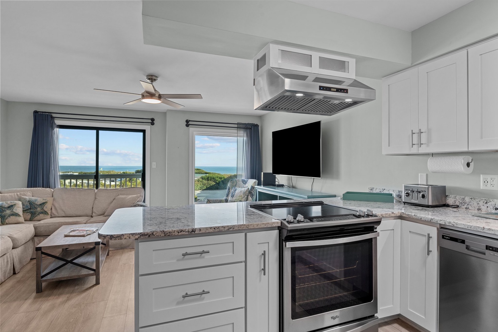 Your open kitchen flows seamlessly into the living space, where ocean views through large windows create the perfect backdrop for cooking and relaxing.