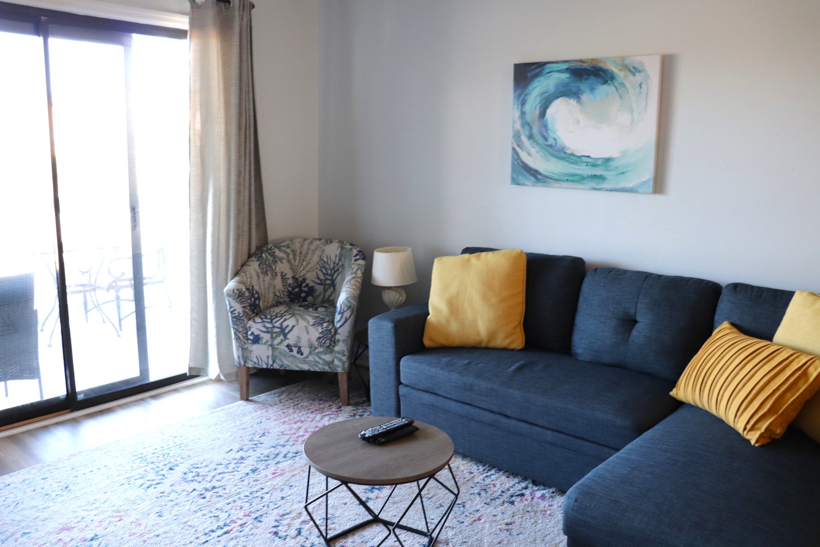 Relax in your stylish living room featuring a plush sectional sofa, cozy accent chair, and sliding door access to your private balcony.