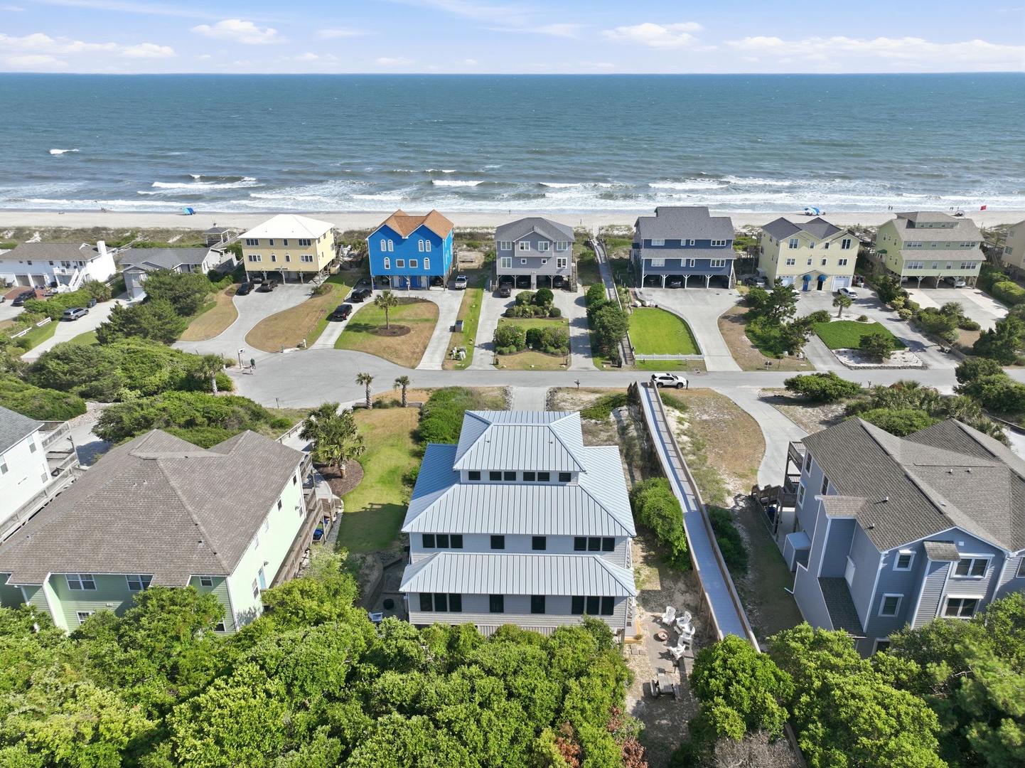 Aerial view of beachfront properties showcasing modern coastal homes with direct beach access, positioned along a scenic shoreline with ocean waves and sandy shores.