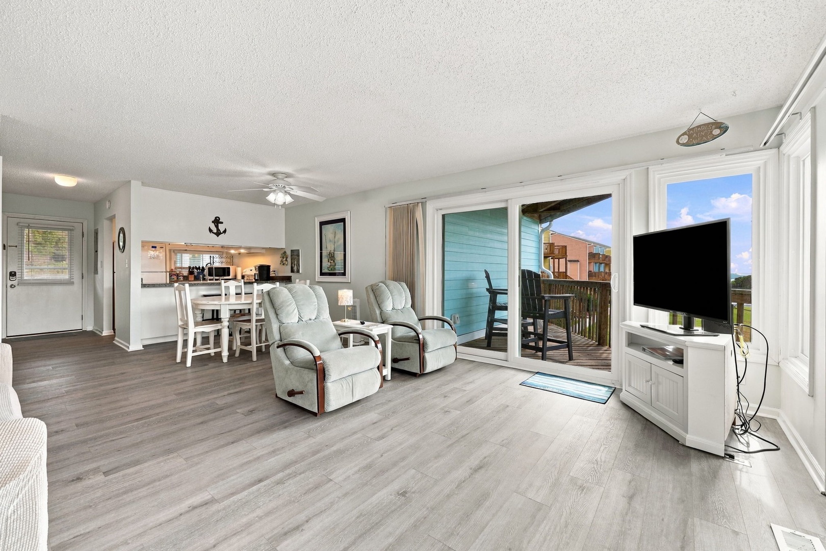 Step into your bright, open living space with comfortable recliners and a welcoming dining area. Floor-to-ceiling glass doors flood the room with natural light and frame your private balcony, where you can relax and unwind.