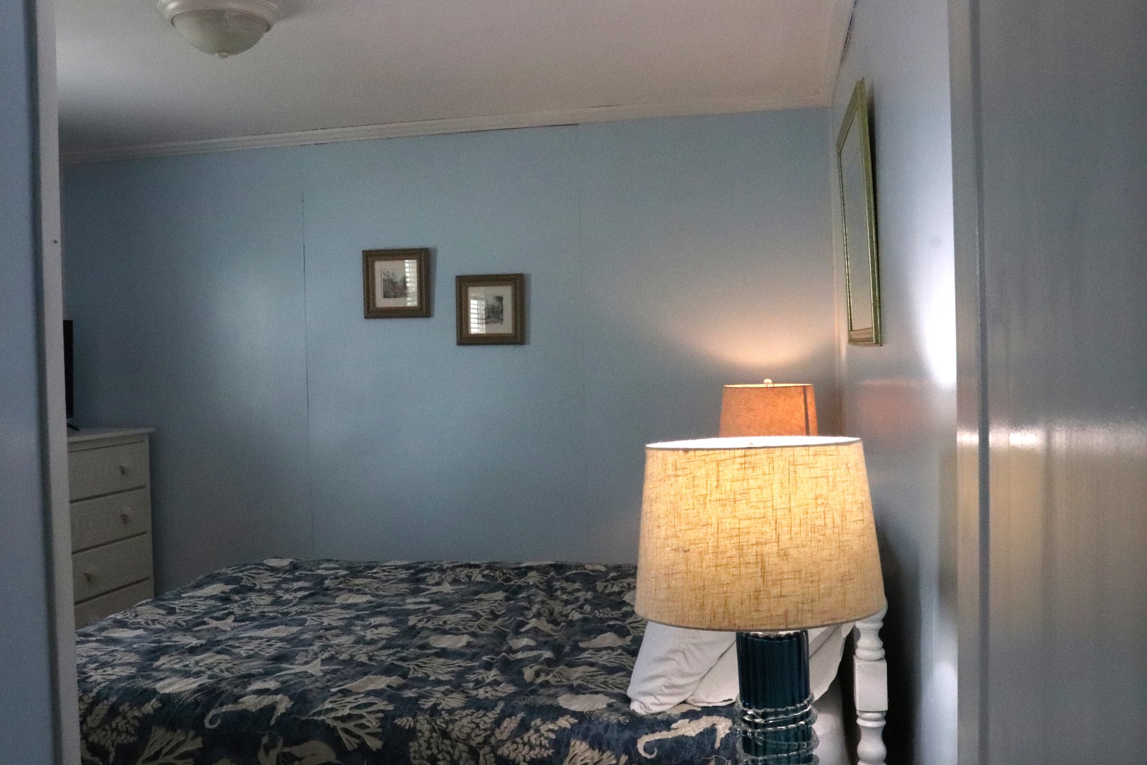 Relax in your serene bedroom, where soft blue walls and warm bedside lighting create a peaceful retreat. Settle into the plush bed adorned with elegant coastal-inspired linens.