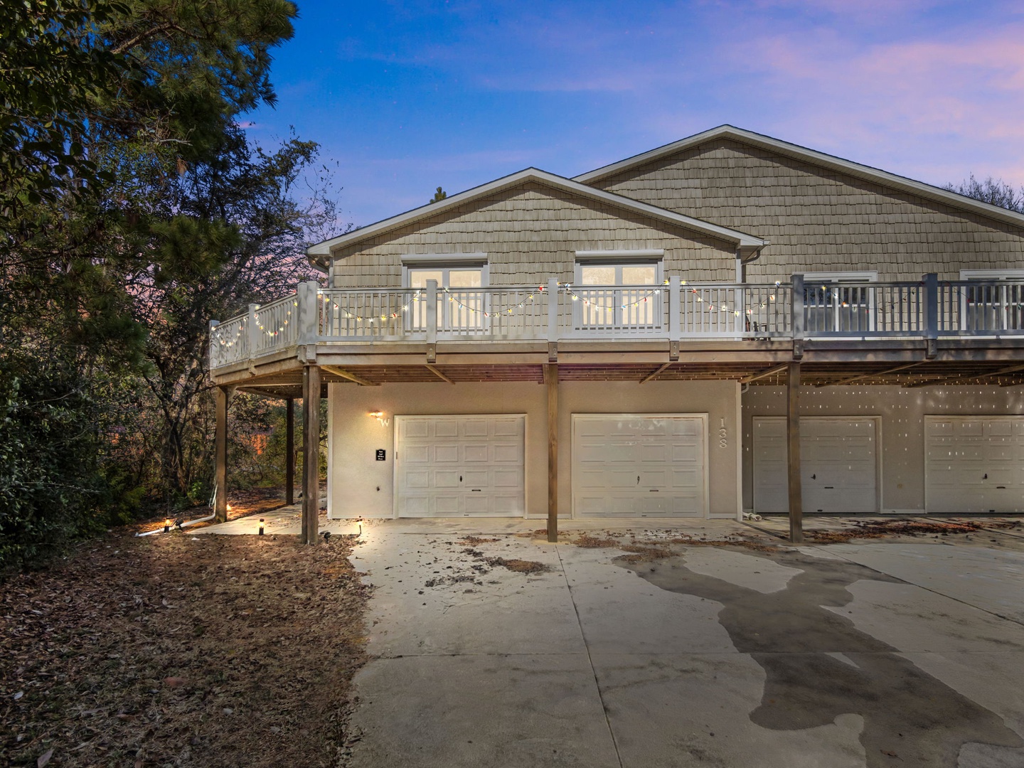 Multi-unit property exterior featuring garage parking and elevated balconies, captured during the golden evening hours.