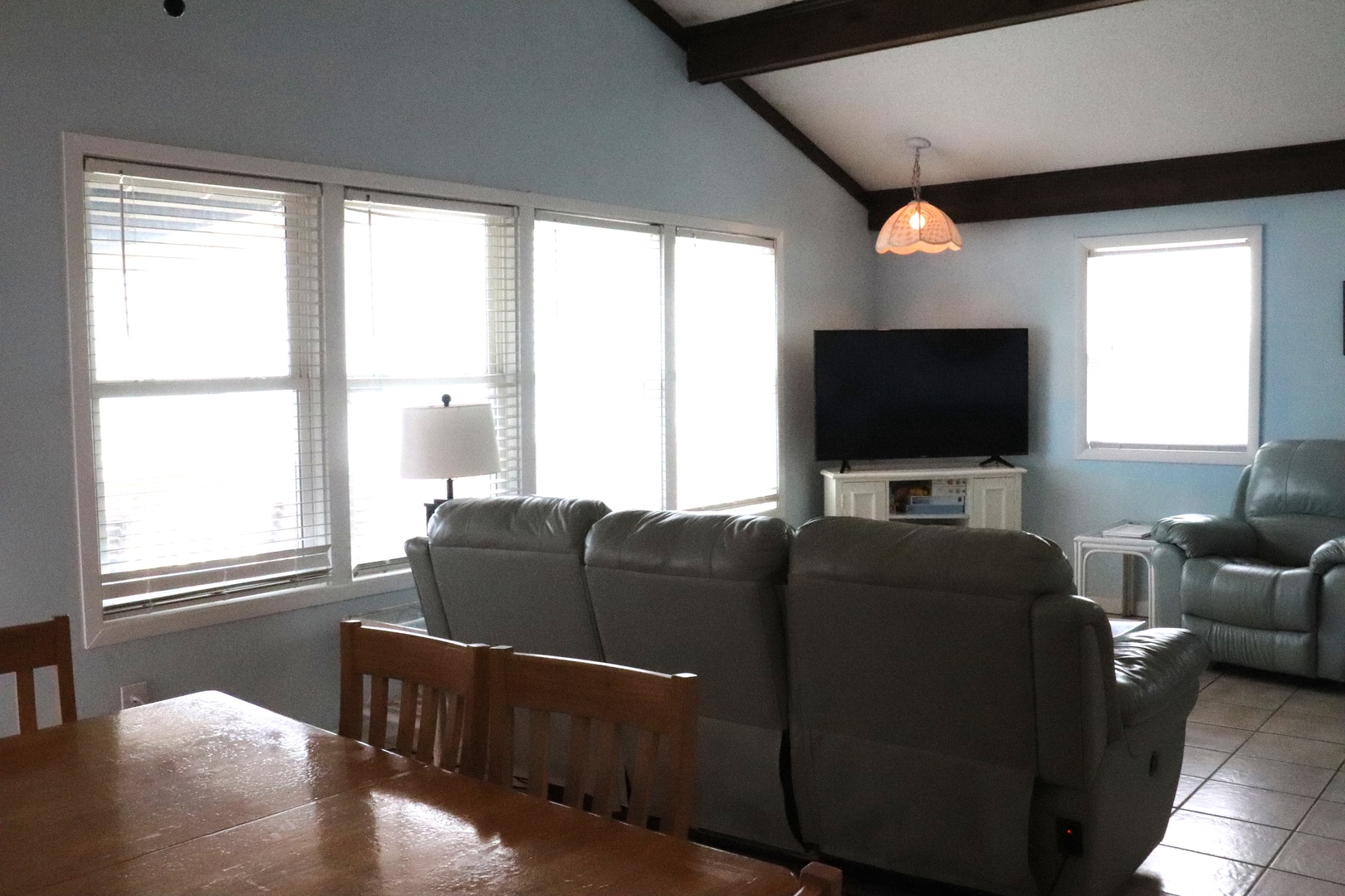 Kick back in this bright living space with plush seating, a large TV for movie nights, and vaulted ceilings that make the room feel open and welcoming.