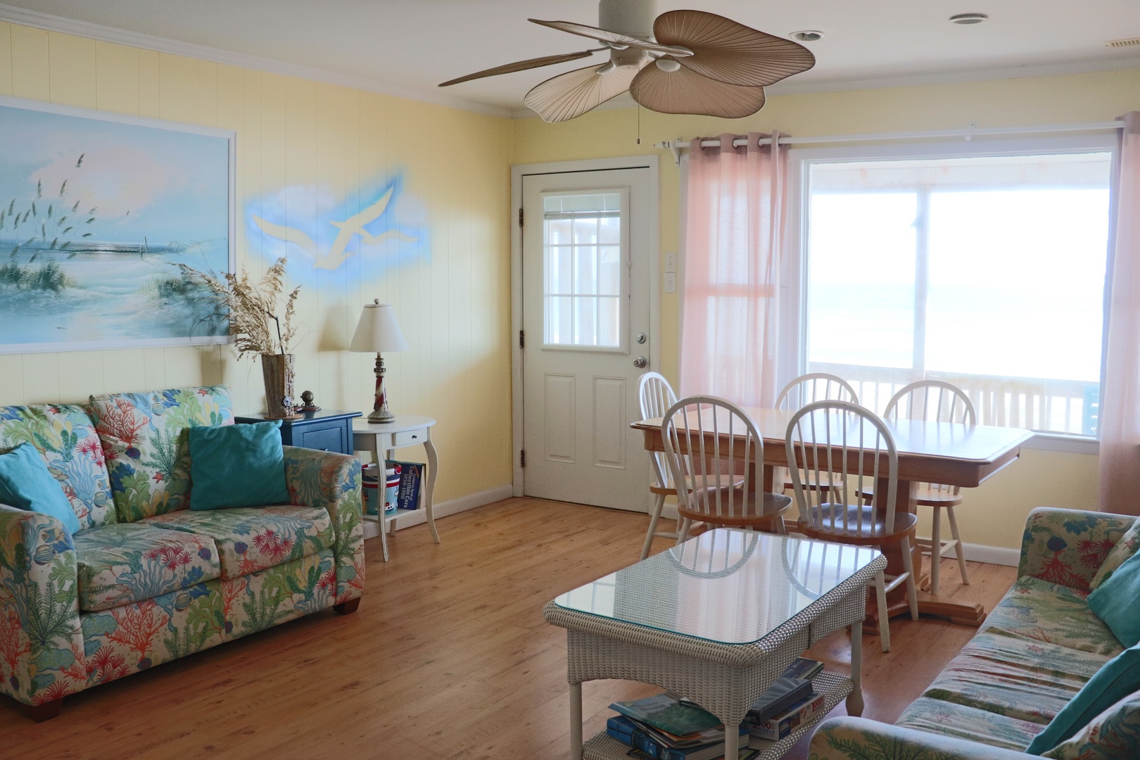 Relax in your coastal retreat with tropical furnishings, ocean artwork, and a breezy ceiling fan creating the perfect beach getaway atmosphere.