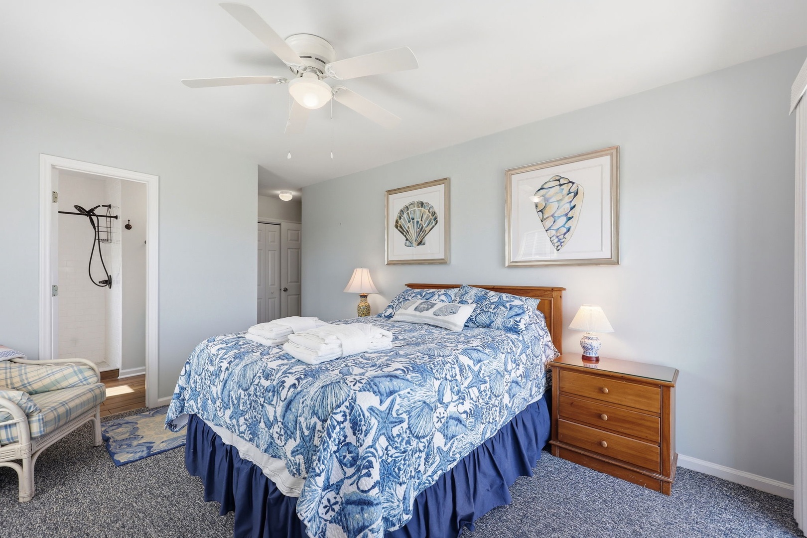 Relax in this serene coastal bedroom with crisp linens, ocean-inspired décor, and gentle ceiling fan. Your peaceful retreat awaits under soft light and calming blue tones.