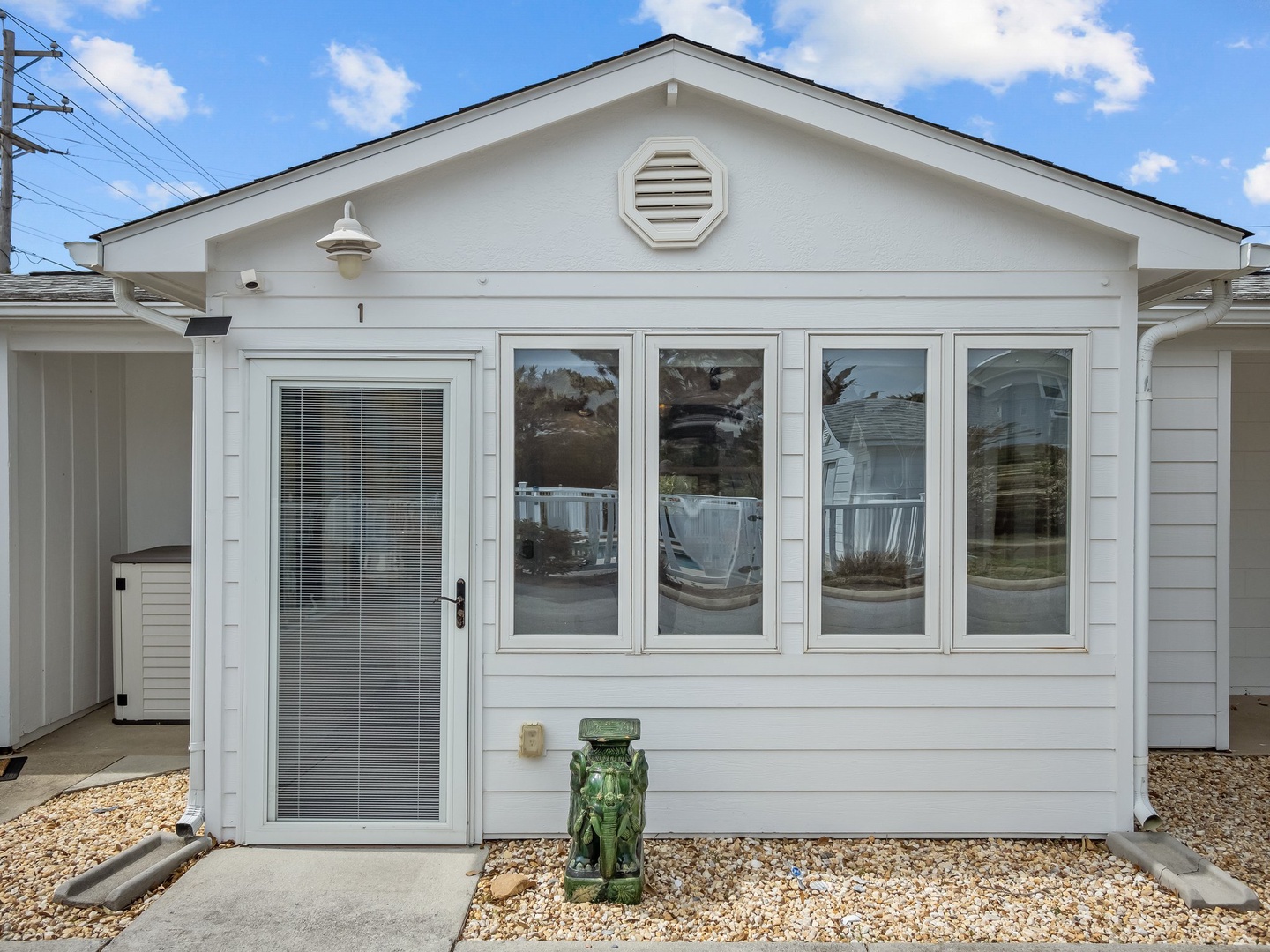 Clean white exterior with large windows and charming decorative touches welcomes guests to this coastal retreat.