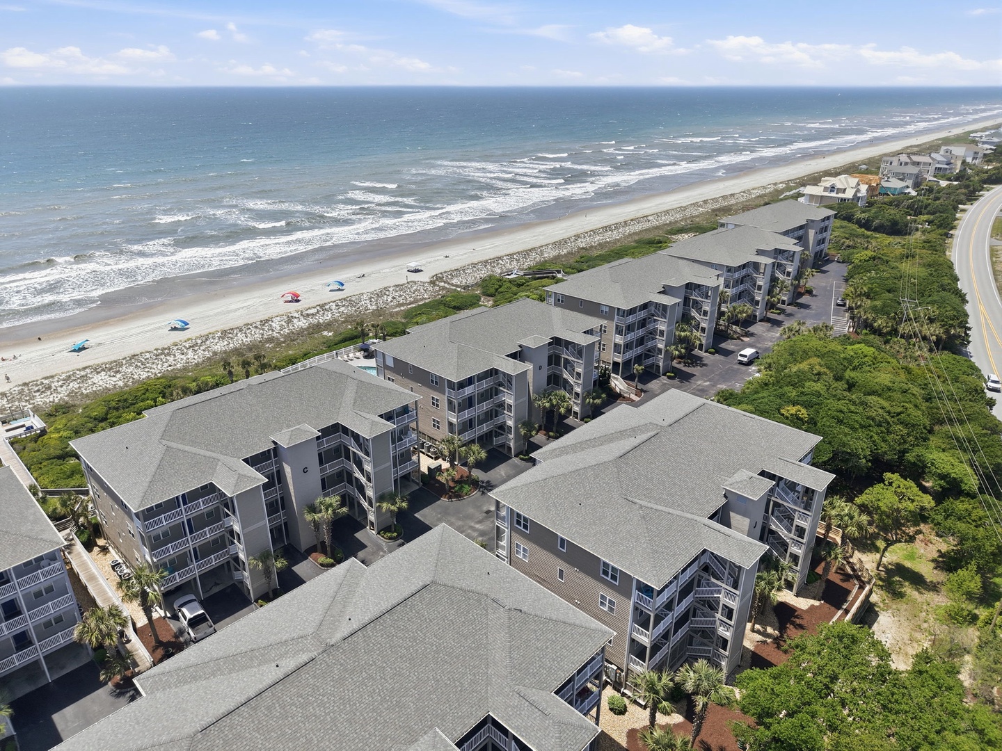 Beachfront property complex with multiple buildings situated along a pristine sandy shoreline, offering convenient beach access and coastal views just steps from the ocean.