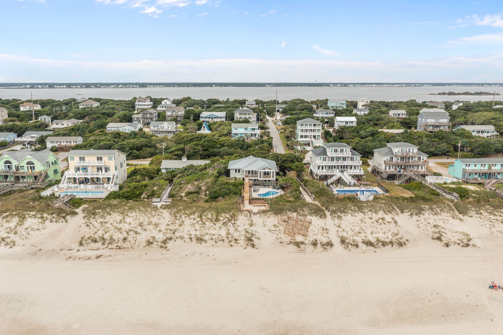 Aerial view of beachfront vacation homes nestled among dunes with private pools and beach access walkways.