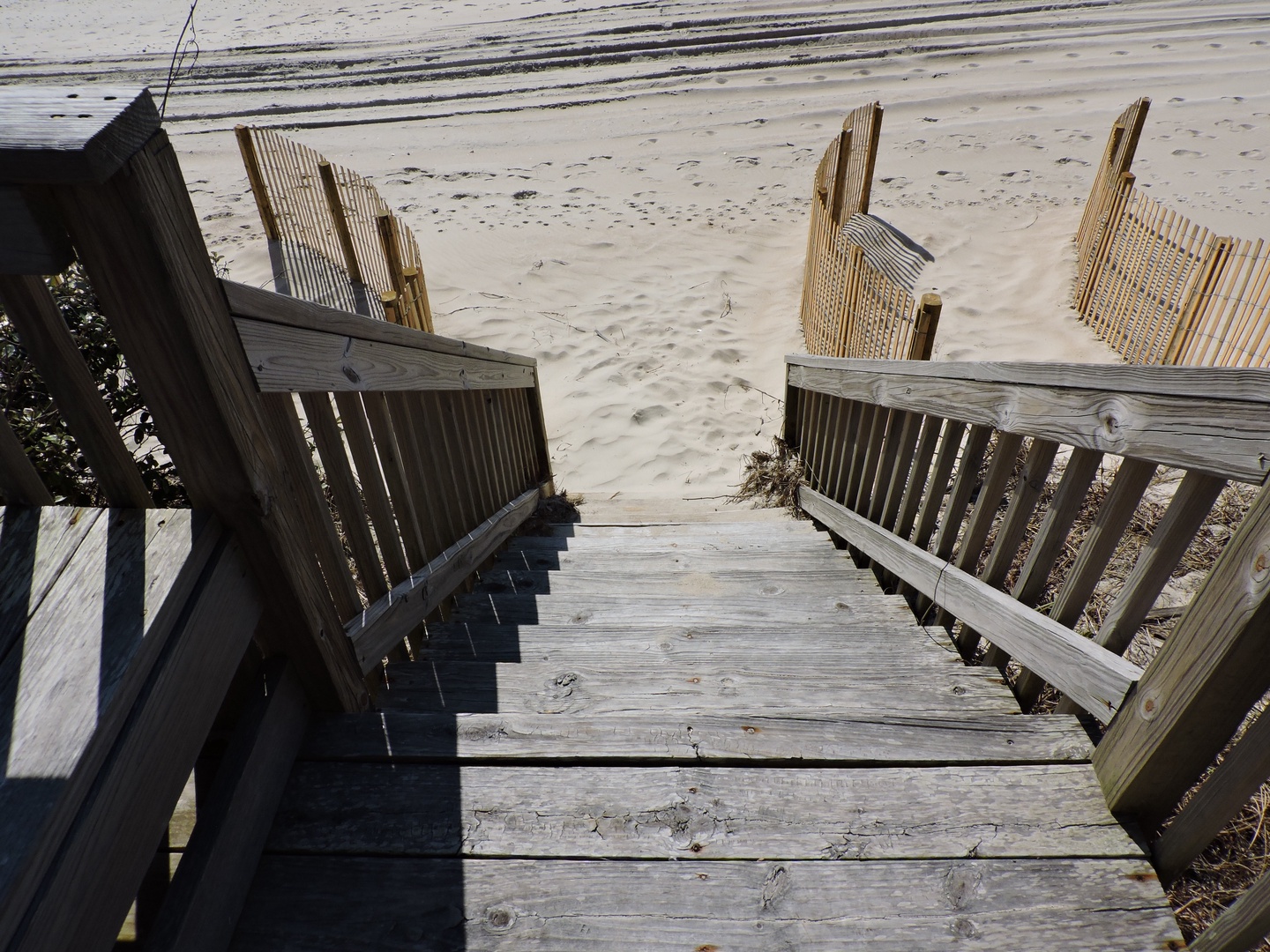 Wooden steps lead down to pristine sandy shores where gentle waves await your peaceful beach days.