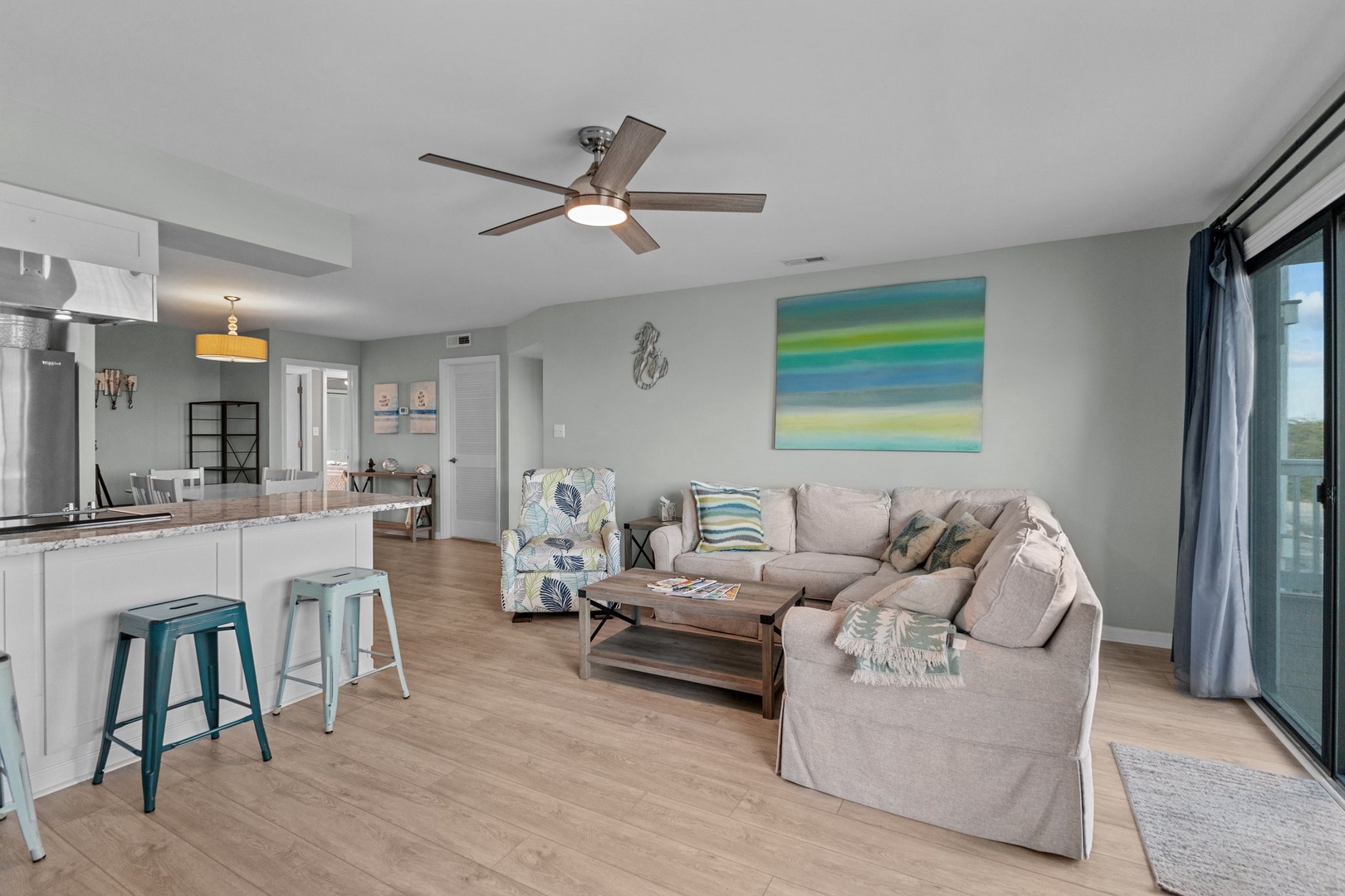 Unwind in your bright, modern living space with plush sectional seating and ocean-inspired decor that creates the perfect coastal retreat atmosphere.