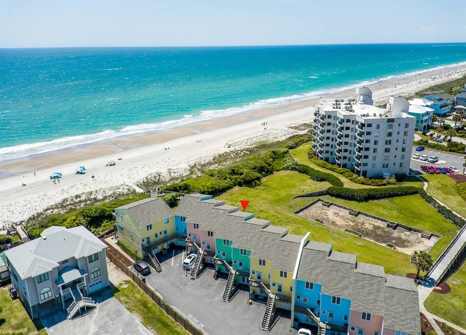 Beachfront property aerial showing pristine coastline with expansive sandy beach and crystal-clear turquoise waters stretching to horizon.