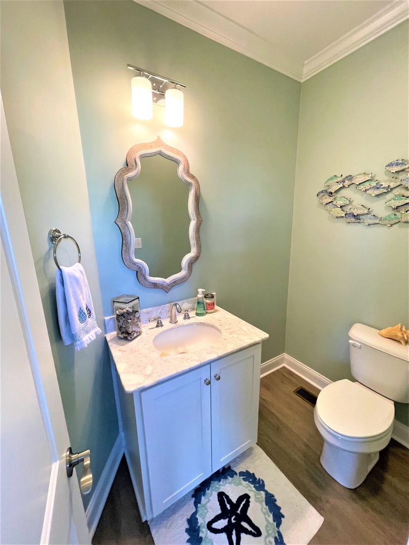Step into your beautifully appointed powder room with calming sage walls, elegant vanity, and charming coastal touches that make freshening up a delight.