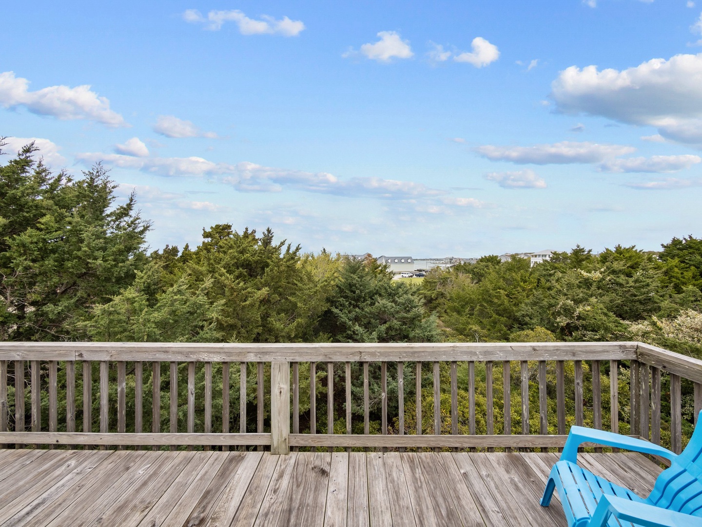 Soak up peaceful moments on your private deck, where bright blue chairs invite relaxation overlooking lush treetops and distant views.