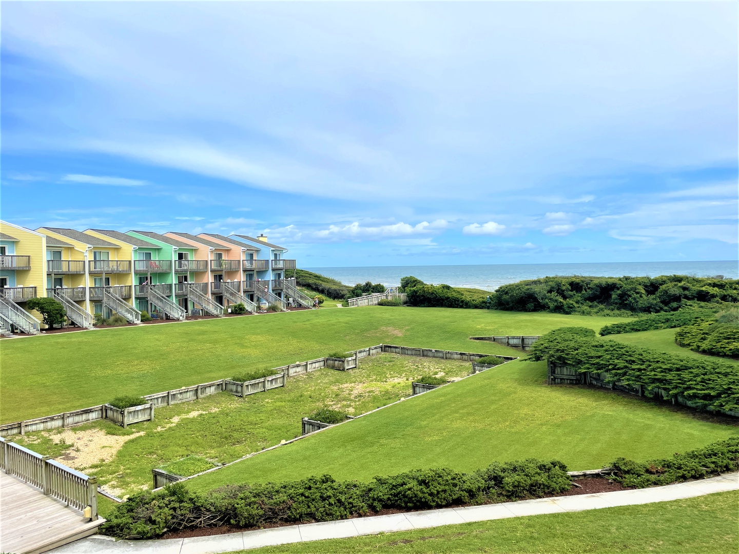 Colorful beachside townhouses overlook expansive green fields leading to the ocean in this coastal retreat community.