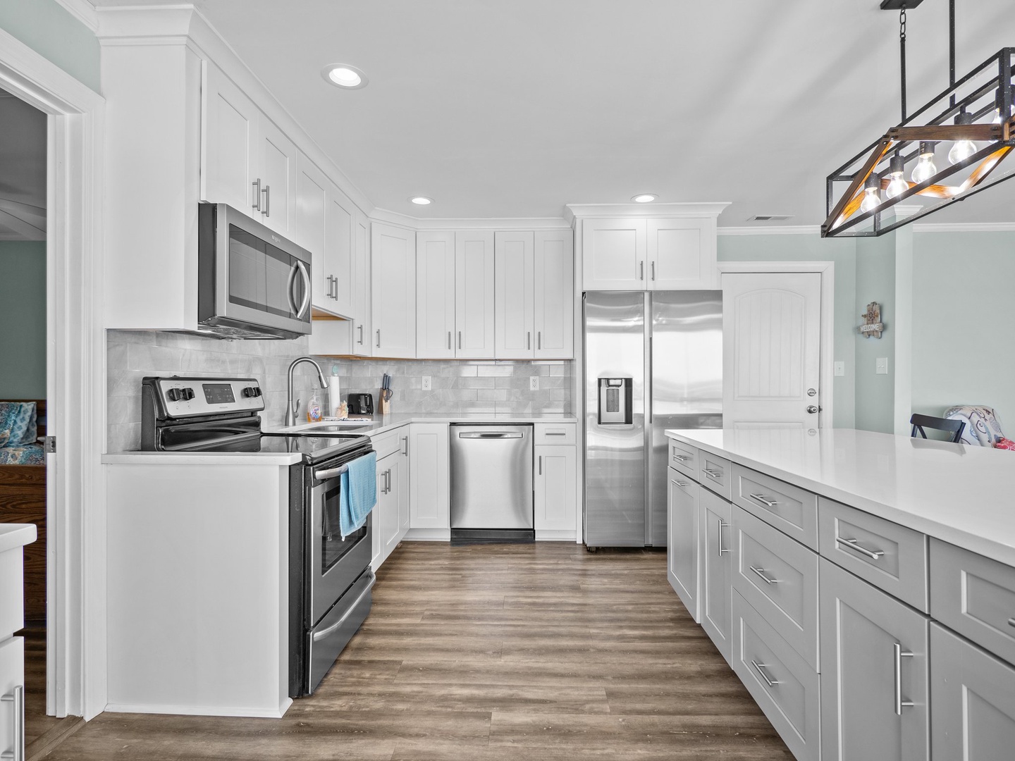 Cook your favorite meals in this bright, modern kitchen with stainless steel appliances and gleaming white countertops.