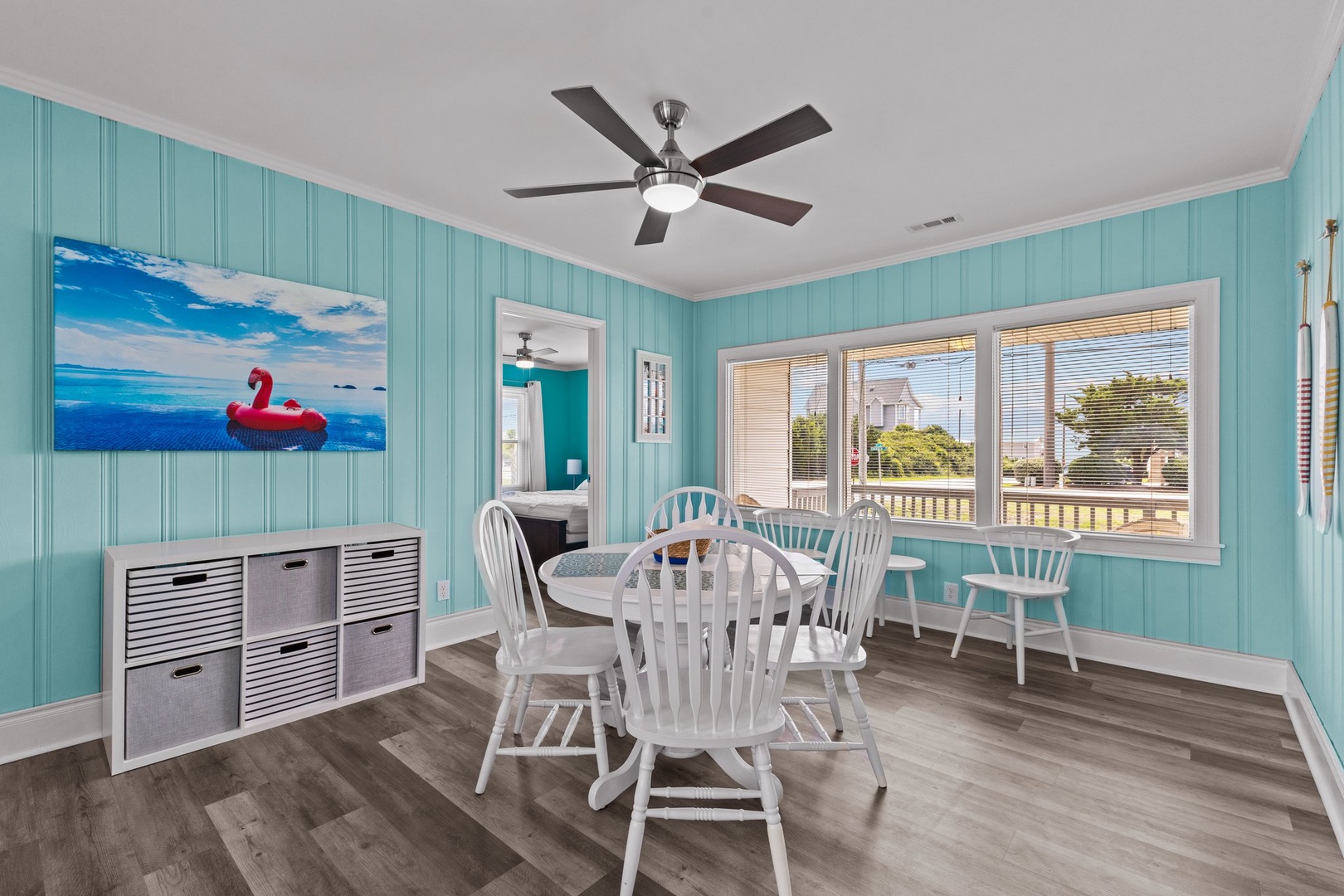 Gather around this charming coastal dining space where turquoise walls and ocean art create the perfect backdrop for your beach vacation meals.