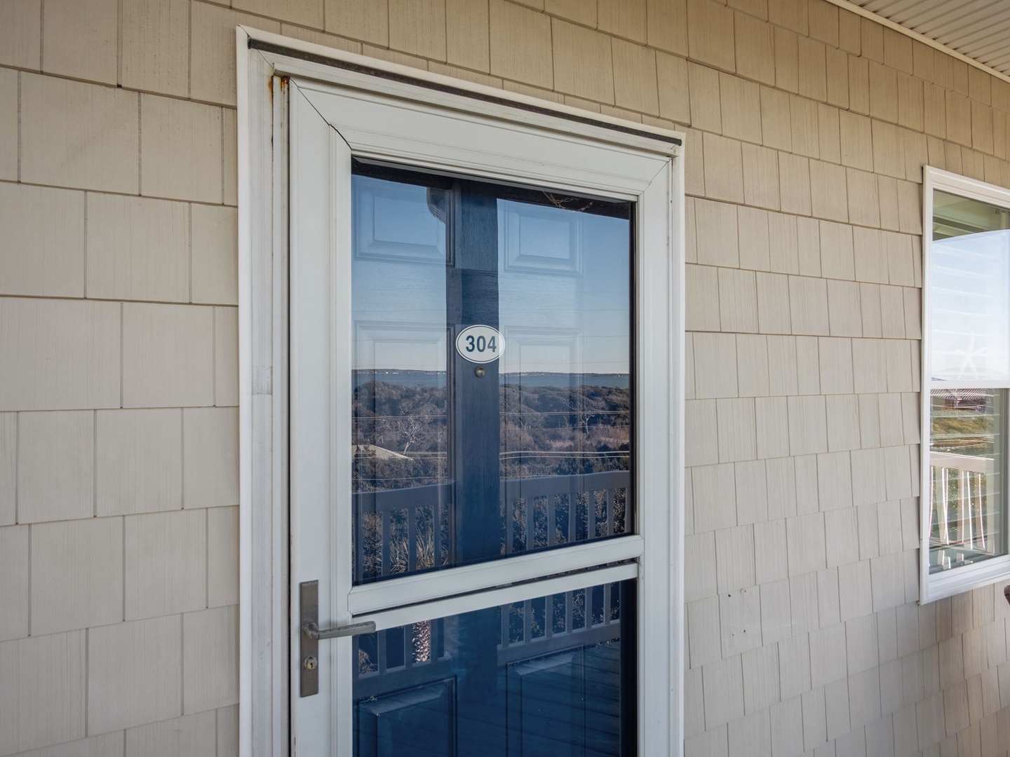 Property entrance marked 304 with natural shingle siding and mountain views reflected in the glass door.