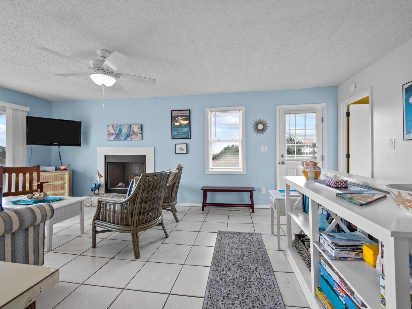 Relax in your bright, coastal living space with soothing blue walls, cozy fireplace, and cheerful natural light streaming through windows.