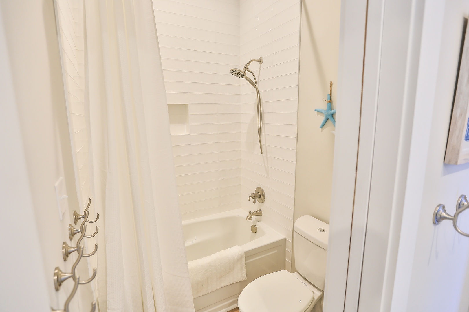 Your bright bathroom features a relaxing tub-shower combo with fresh white towels and coastal decor touches.