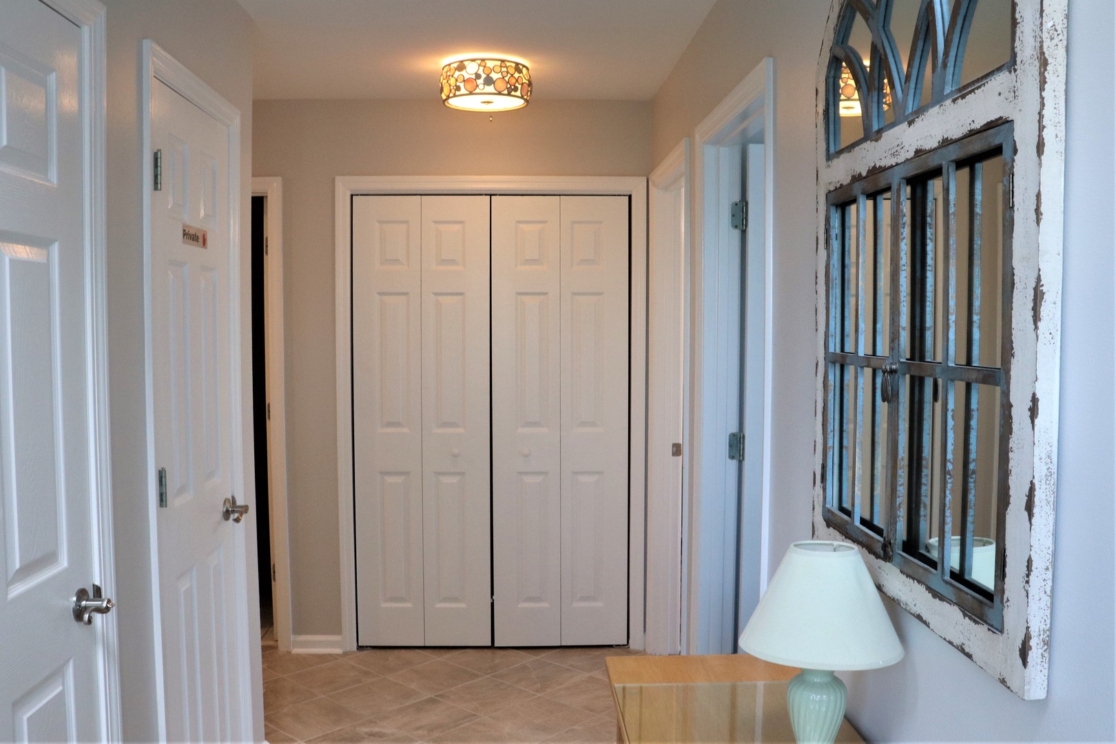 Step into your welcoming hallway where rustic charm meets modern comfort. The decorative ceiling fixture casts warm light over clean, organized storage.
