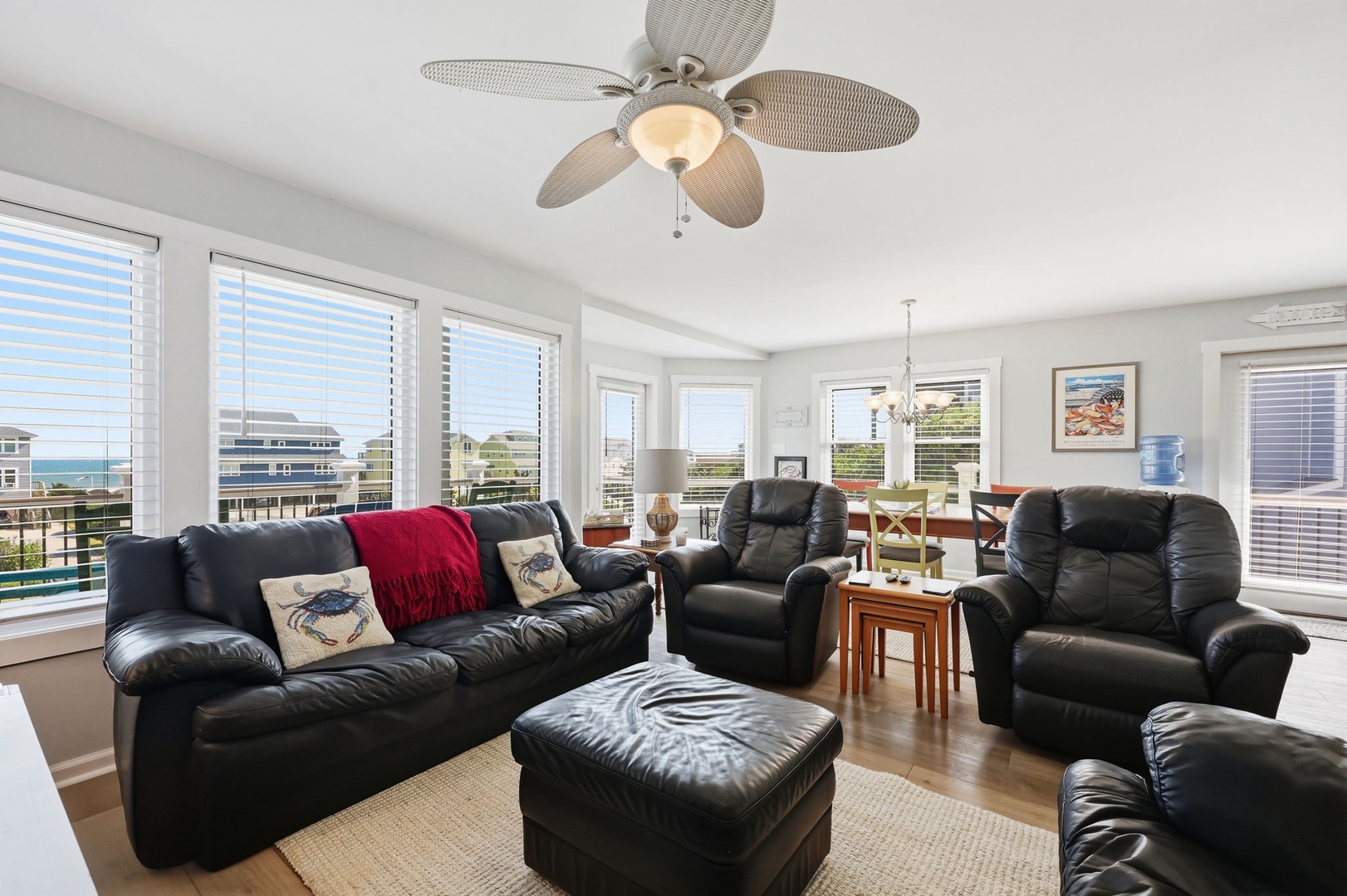 Sink into plush leather seating and enjoy ocean glimpses through bright windows. The coastal fan overhead keeps your space comfortable while you relax in this inviting living area.