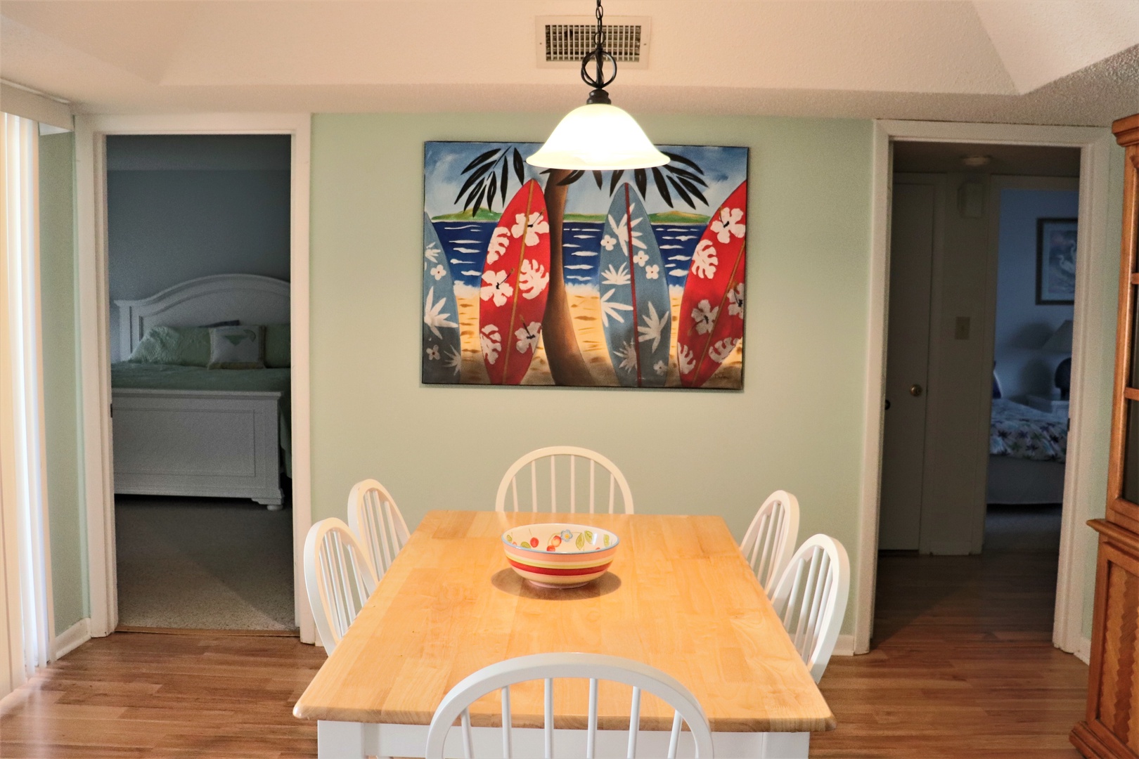 Gather around this cheerful dining table for memorable meals with loved ones, featuring tropical artwork that sets a relaxed vacation mood.