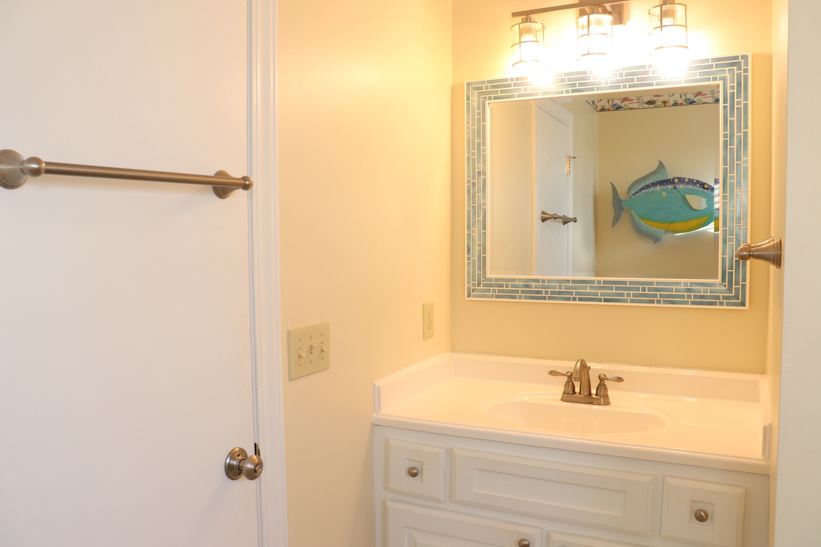 Freshen up in your bright, cheerful bathroom featuring a nautical-themed mirror and warm vanity lighting for your morning routines.