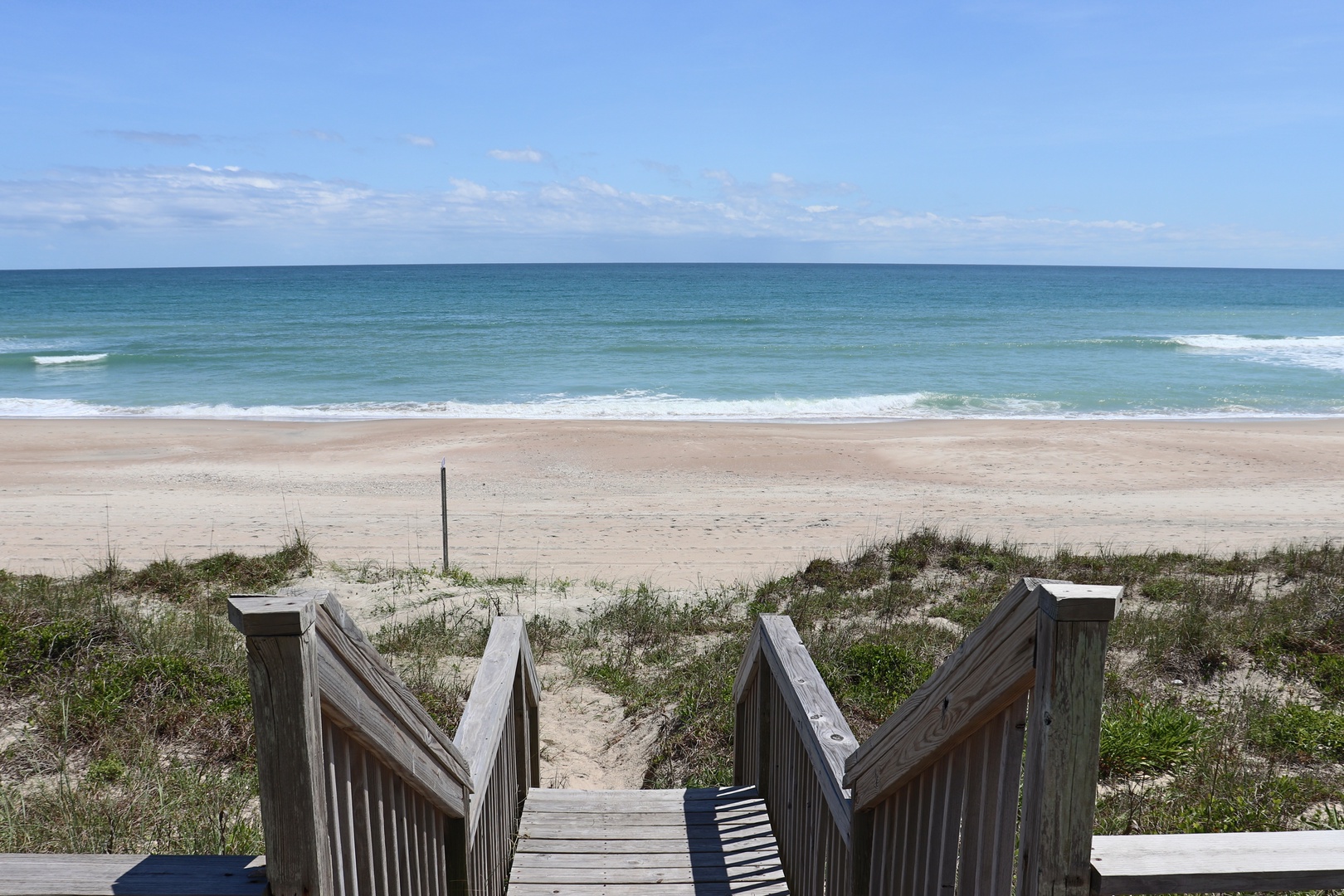 Pristine beachfront with direct access via wooden walkway, where endless ocean views and gentle waves await.