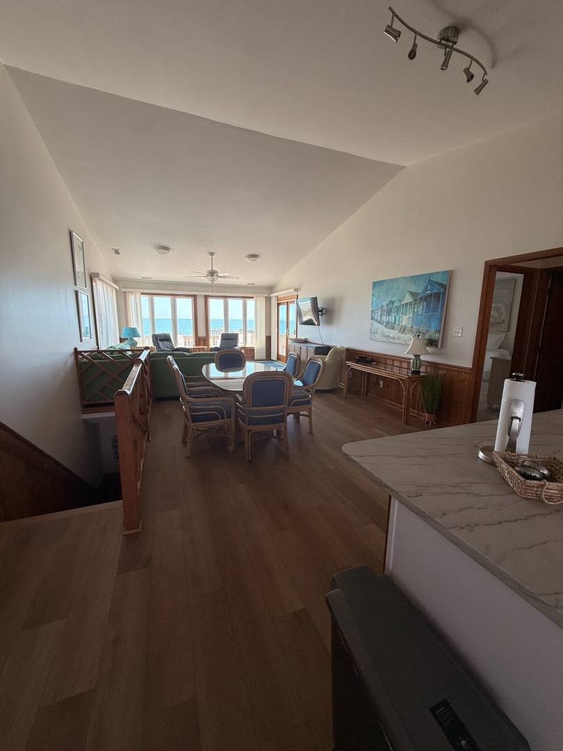 Step into your open-concept living space, where floor-to-ceiling windows frame endless ocean views. The inviting living room flows into the dining area and full kitchen, offering plenty of room to unwind, dine, and make yourself at home.