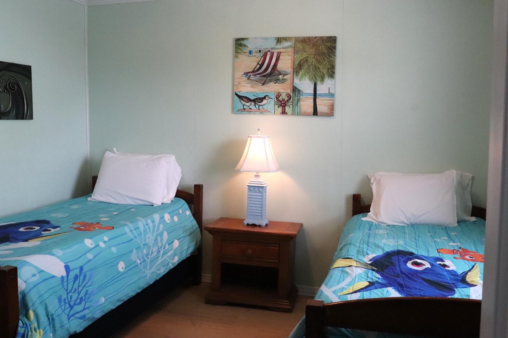 Your beachside bedroom awaits, featuring twin beds with vibrant ocean-themed bedding, soothing coastal décor, and warm lighting to make you feel right at home after a day exploring.