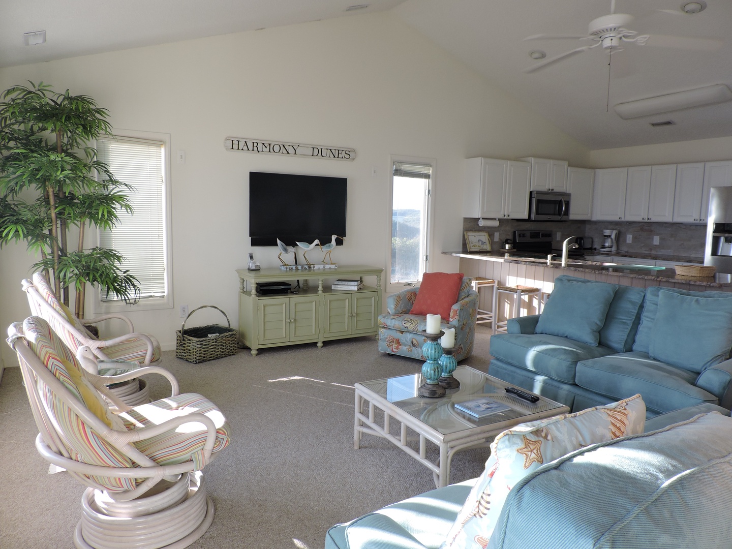 Relax in your coastal living room with comfortable seating, entertainment center, and kitchen nearby for easy vacation living.