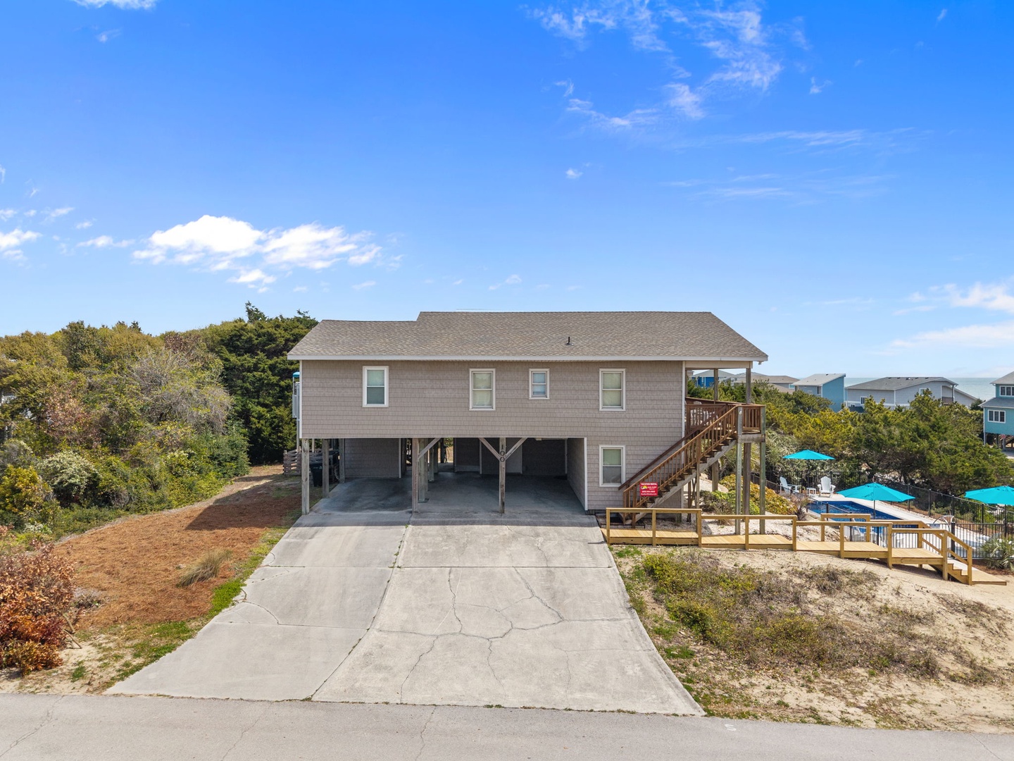 Beach house with elevated design and coastal charm, featuring convenient ground-level parking and outdoor deck access in a peaceful neighborhood setting.