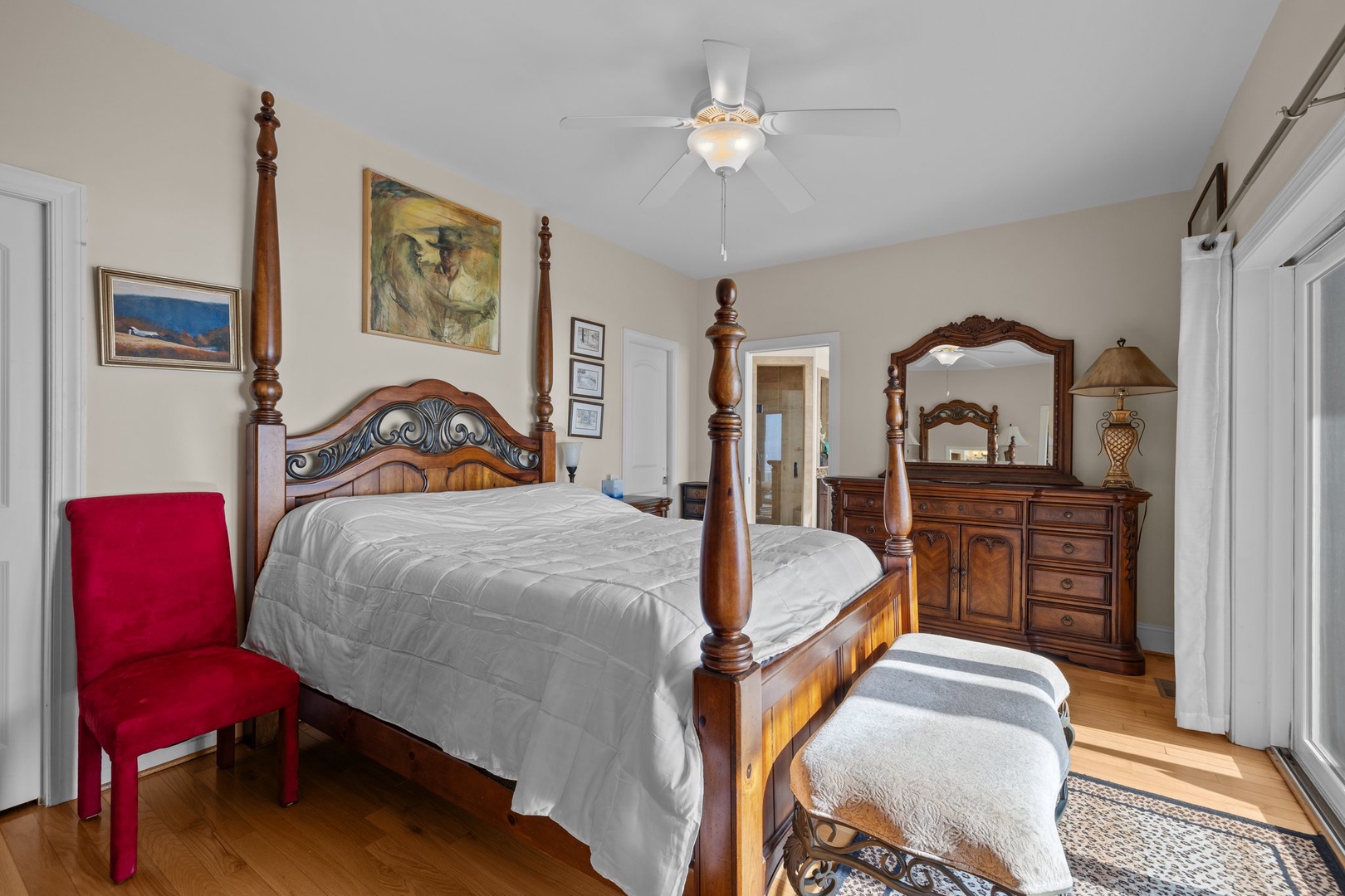 Unwind in your elegantly appointed bedroom featuring a stunning four-poster bed, rich wood furnishings, and artwork that creates a warm, sophisticated retreat.