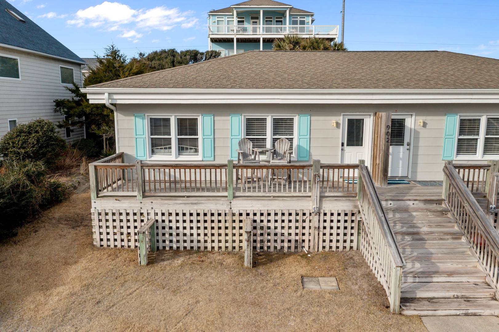 Charming beach cottage with turquoise shutters and spacious deck for morning coffee and coastal breezes.