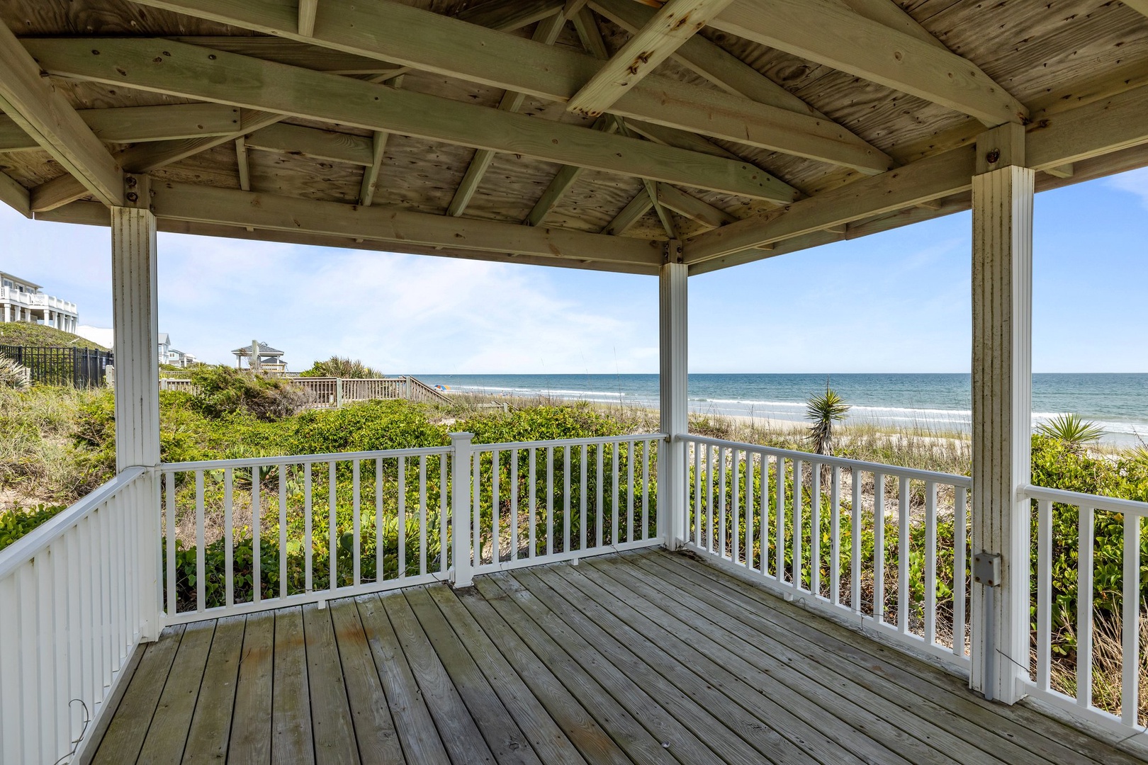Covered beachfront deck offering panoramic ocean views and direct beach access through coastal dunes.