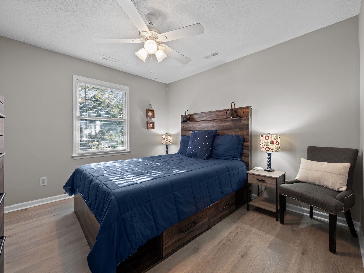 Unwind in your cozy bedroom with rustic wood accents, crisp navy bedding, and natural light streaming through your window.