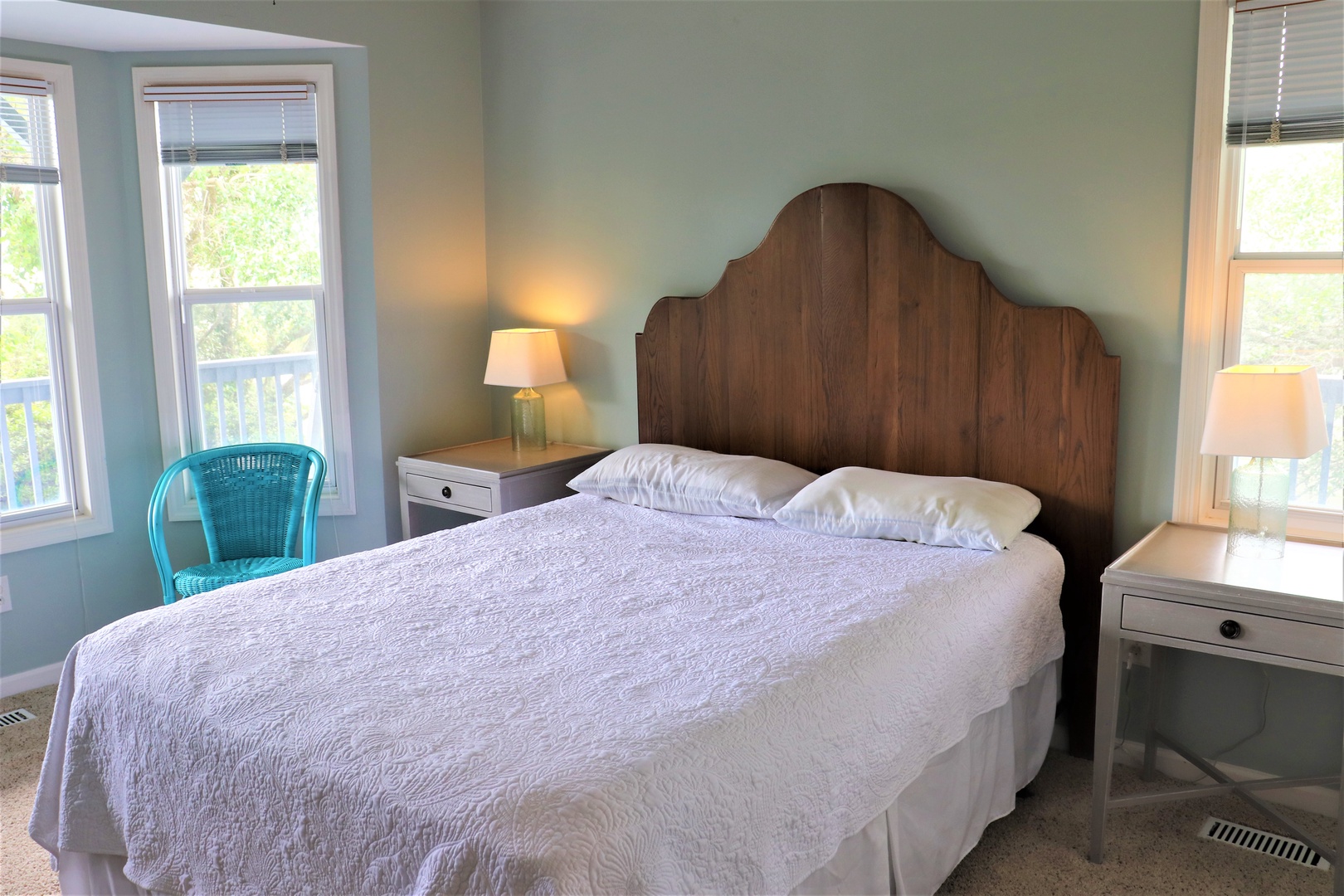 Drift off to sleep in this tranquil bedroom featuring a rustic wooden headboard and crisp white linens, with gentle natural light streaming through your windows.