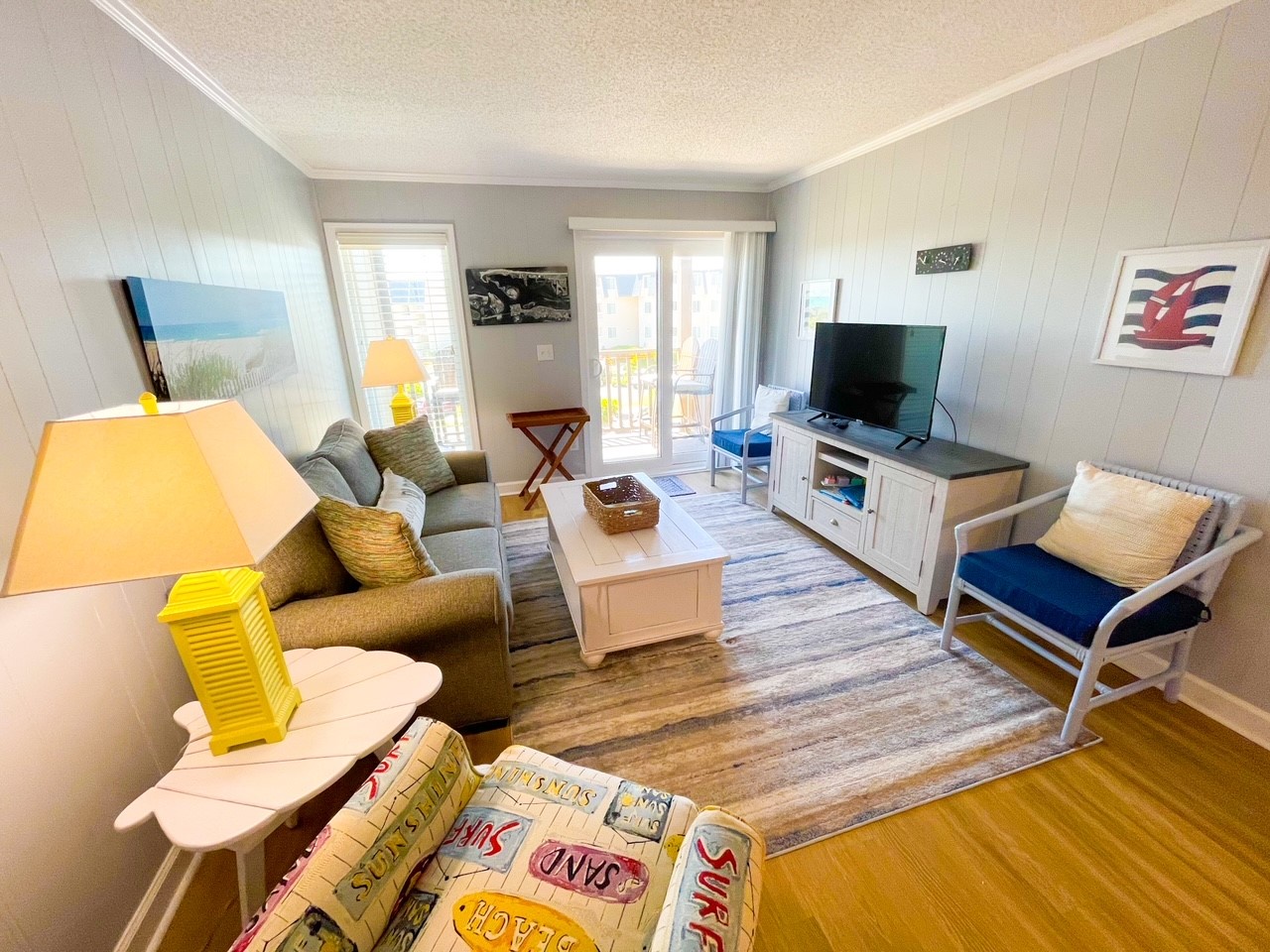 Unwind in your bright, coastal-inspired living room with plush seating and ocean artwork creating the perfect seaside retreat atmosphere.