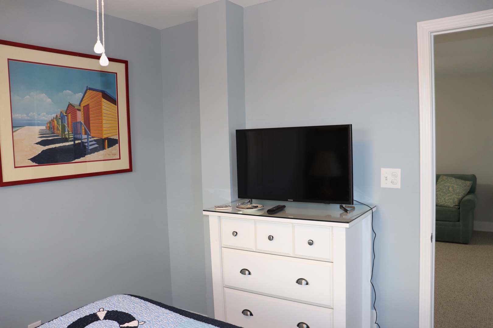 Your bedroom features a flat-screen TV and dresser for storage, with coastal artwork creating a relaxing seaside atmosphere.
