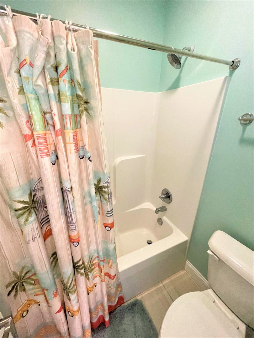 Freshen up in your cheerful bathroom with its tropical-themed curtain and soothing mint walls, perfect for relaxing after beach adventures.